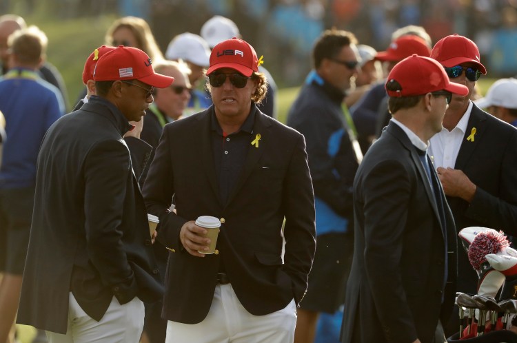 Tiger Woods, left, and Phil Mickelson, center, of the U.S. wait for the closing ceremony after another dismal showing at the Ryder Cup, which ended Sunday in a 171/2-101/2 victory for Europe.