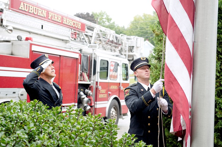 Auburn fire Capt. Chip Keene, left, and firefighter Ryan Demers raise the American flag during the 9/11 Memorial Ceremony at Central Station on Tuesday. 