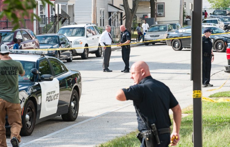 Lewiston police officers, detectives and other law enforcement officials confer Wednesday in the middle of Knox Street in Lewiston, where a man with stab wounds collapsed after running out of the nearby parking lot of a housing development.