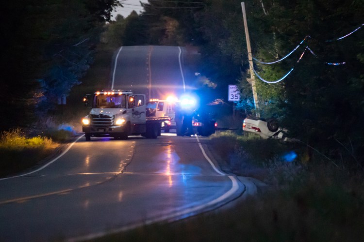 A wrecker arrives on scene and hauls the remains of a white passenger car from the woods of the Thurston Hill Rd, west of State Route 201 on Saturday evening. 