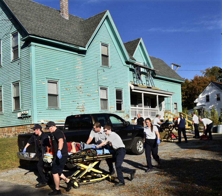 Two men are transported on gurneys by rescue personnel to the hospital after falling from scaffolding, background, while working on a home on Brook Street in Waterville on Wednesday morning.