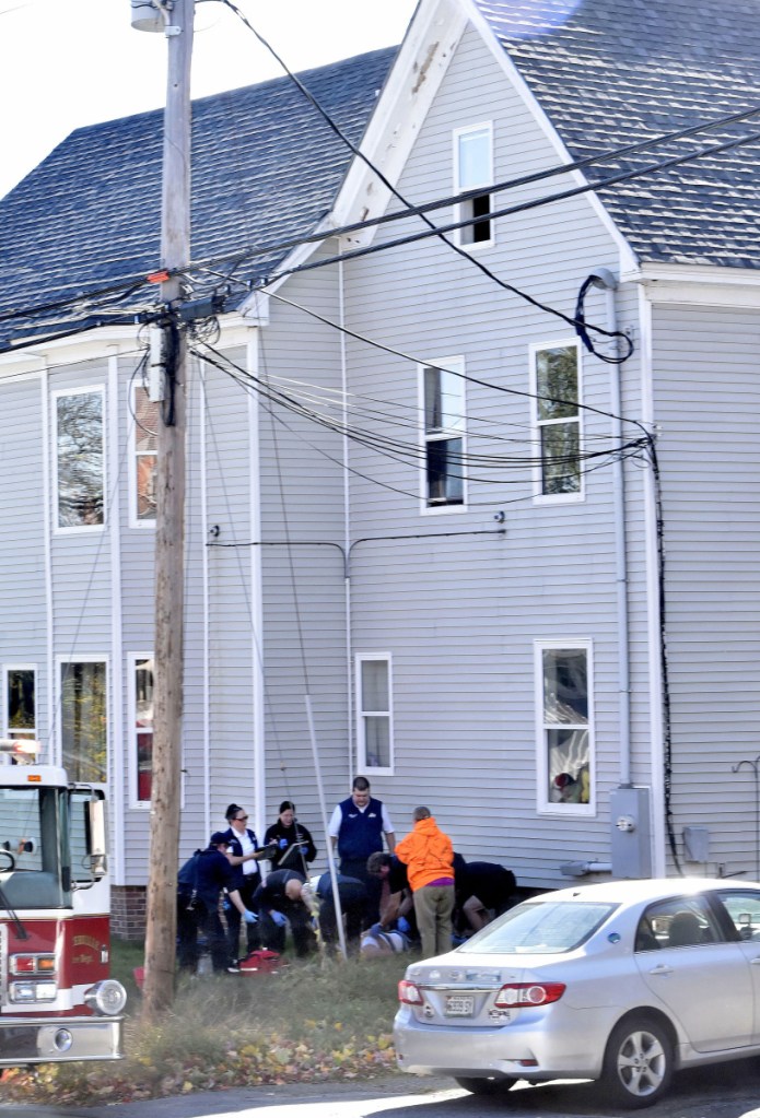 Rescue and ambulance personnel administer aid before transporting a man who reportedly fell Tuesday from the open third floor window, above, at the Home Place Inn, an apartment complex on College Avenue in Waterville.