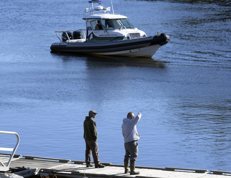 Friends and family watch Friday as the Marine Patrol searches the Kennebec River in Richmond for Mark Johnston, 64. Authorities searched by air, on the water and in the water after Johnston went missing Thursday night.