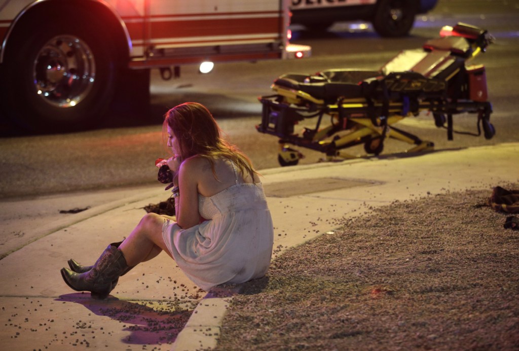 A woman sits on a curb at the scene of a shooting outside a music festival on the Las Vegas Strip on Oct. 2, 2017. It took 11 minutes for the gunman in the deadliest mass shooting in modern U.S. history to kill 58 people. Then he killed himself. A year later, Las Vegas police and the FBI have still found no motive for the rampage.