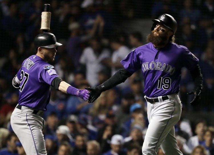 Colorado's Charlie Blackmon, right, celebrates with Trevor Story after scoring on a sacrifice fly by Nolan Arenado against the Chicago Cubs on Tuesday night.