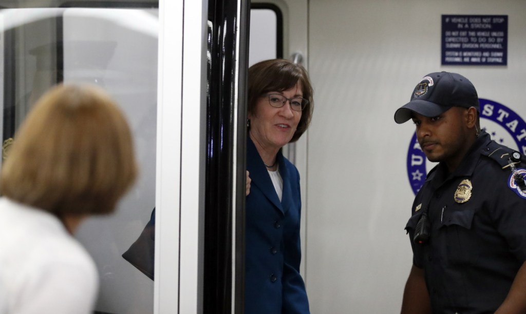 Sen. Susan Collins, R-Maine, responds to a reporter's question Wednesday as she is accompanied by a Capitol Police officer. The corridors outside her office were kept clear by police Wednesday, apparently because of security concerns.