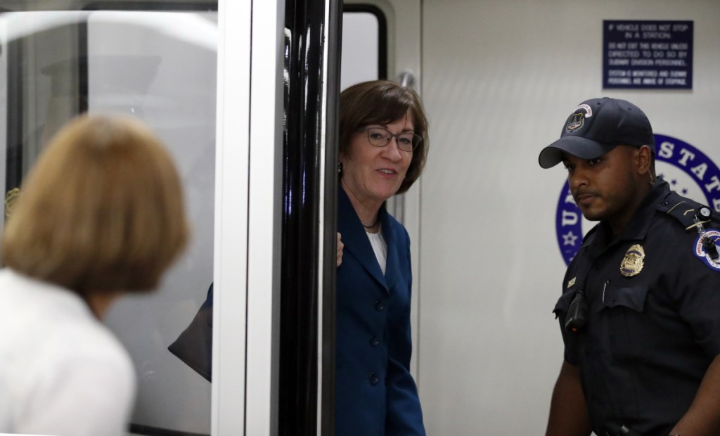Sen. Susan Collins, R-Maine, center, responds to a reporter's question as she is accompanied by a Capitol Hill Police officer on Wednesday in Washington.