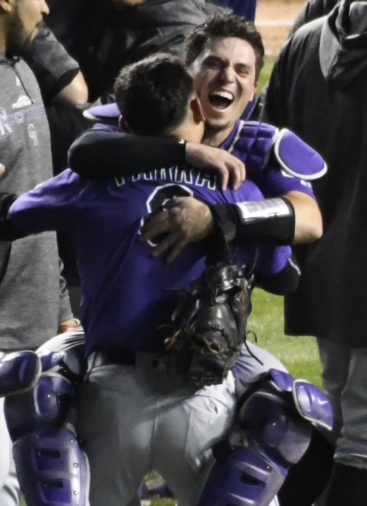 Rockies catcher Tony Wolters, rear, and left fielder Gerardo Parra celebrate Tuesday's 13-inning win at Chicago.