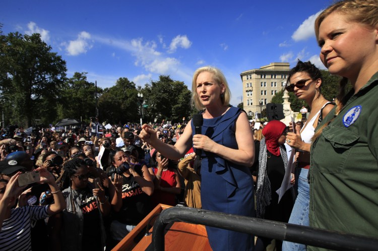 Sen. Kirsten Gillibrand, D-N.Y., with actress and comedian Amy Schumer, right, and actress model Emily Ratajkowski, center, speaks at a rally against Supreme Court nominee Brett Kavanaugh at the Supreme Court in Washington on Thursday.