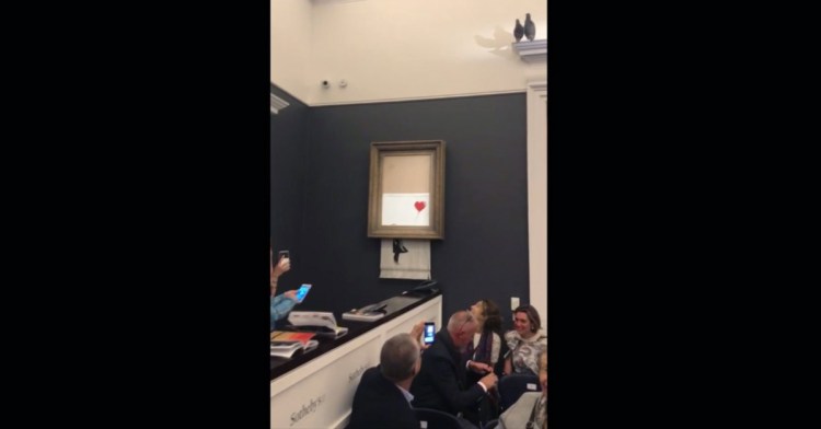 In this screen grab taken from video Friday, people watch as the spray-painted canvas "Girl With Balloon" by Banksy is shredded at Sotheby's in London.