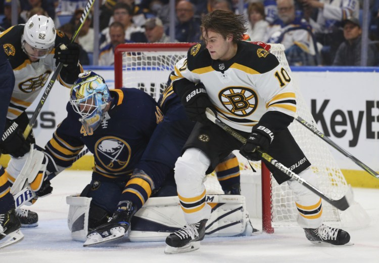 Boston forward Anders Bjork looks for the loose puck after losing his helmet in front of Buffalo Sabres goalie Carter Hutton on Thursday in Buffalo N.Y.