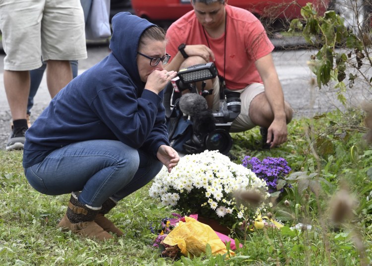 A woman places flowers on Sunday near the place where 20 people died after a limousine crashed into a parked SUV a day earlier in Schoharie, N.Y.