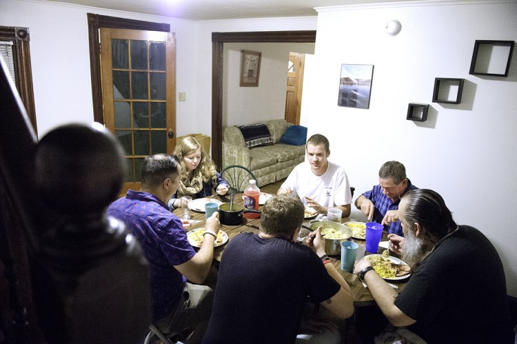 Jesse Harvey, back center, has dinner with residents of Journey House, a Lewiston home for men in recovery from substance abuse disorders. Harvey, the founder of Journey House, is in the process of opening a recovery house in Auburn for women.