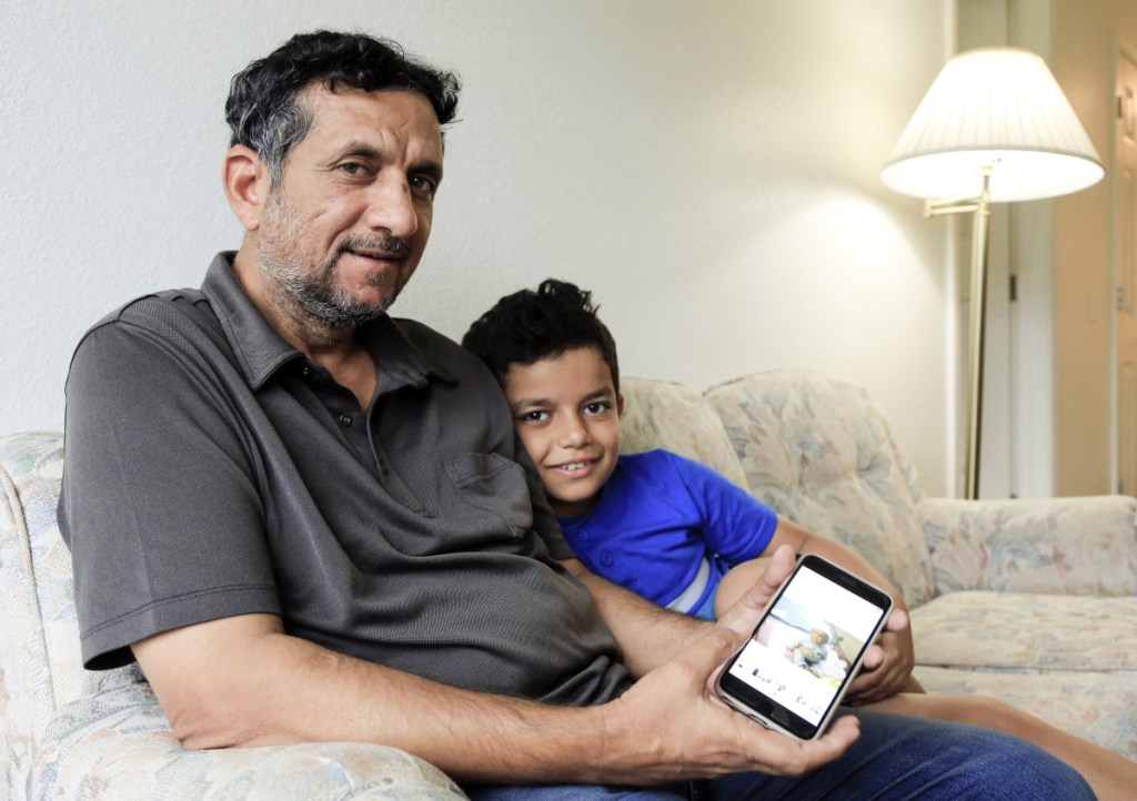 Hadi Mohammed sits with his 9-year-old son Mohammed Ghaleb, as he displays a photo of his son as a baby in Baghdad, in their Lincoln, Neb. apartment. Death threats drove Hadi Mohammed out of Iraq and to a small apartment in Nebraska, where he and his two young sons managed to settle as refugees. But the danger hasn't been enough to allow his wife to join them.
