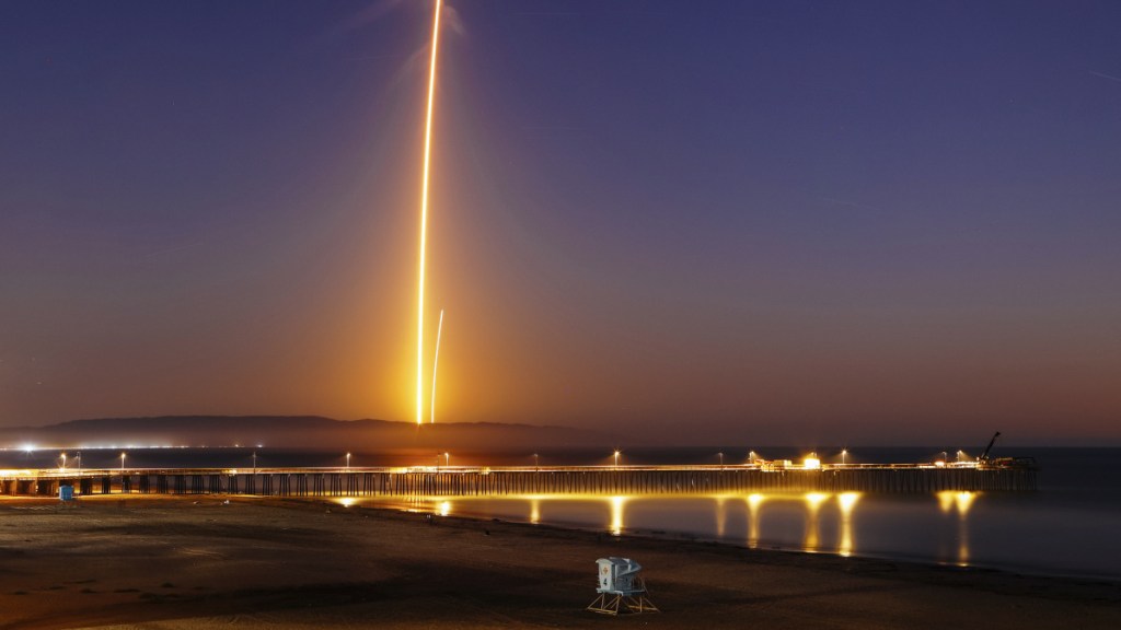 Two streaks in this long-exposure photo show a SpaceX Falcon 9 rocket lifting off, left, from Vandenberg Air Force Base as seen from Pismo Beach, Calif., on Sunday, and then its first stage returning, right, to Earth at a nearby landing pad.