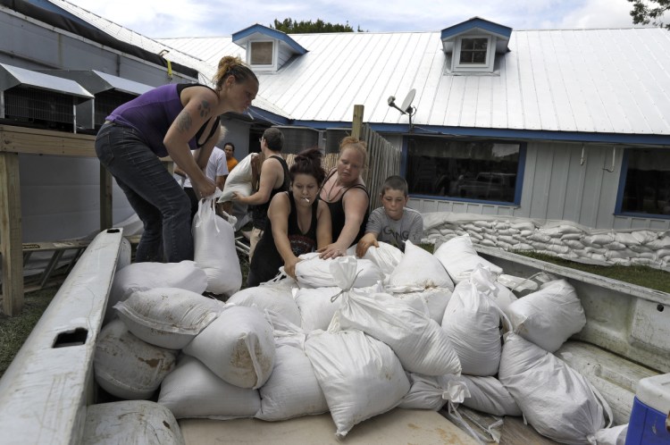 Krystal Day, of Homosassa, Florida, left, leads a sandbag assembly line at the Old Port Cove restaurant Tuesday in Ozello, Florida. Employees were hoping to protect the restaurant from floodwaters as Hurricane Michael continues to churn in the Gulf of Mexico heading for the Florida Panhandle.