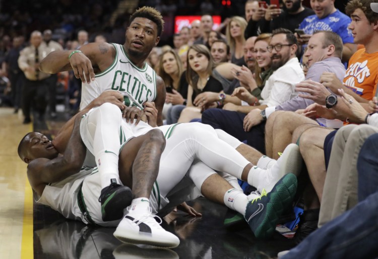 Marcus Smart of the Celtics is held back by teammates during an NBA preseason game Saturday night at Cleveland. Smart was defending a teammate and got ejected for butting in and fined $25,000.