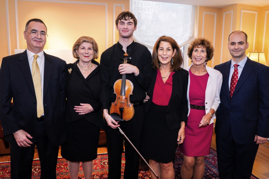 In this photo provided by Chris Lee, Juilliard student Nathan Meltzer, center, poses with the "Ames, Totenberg" Stradivari of 1734 violin loaned to him by the daughters of the late violinist Roman Totenberg, Tuesday, Oct. 9, 2018 in New York. From left are Bruno Price, of Rare Violins of New York, Nina Totenberg, Meltzer, Amy Totenberg, Jill Totenberg and Ziv Arazi or Rare Violins of New York. (Chris Lee via AP)