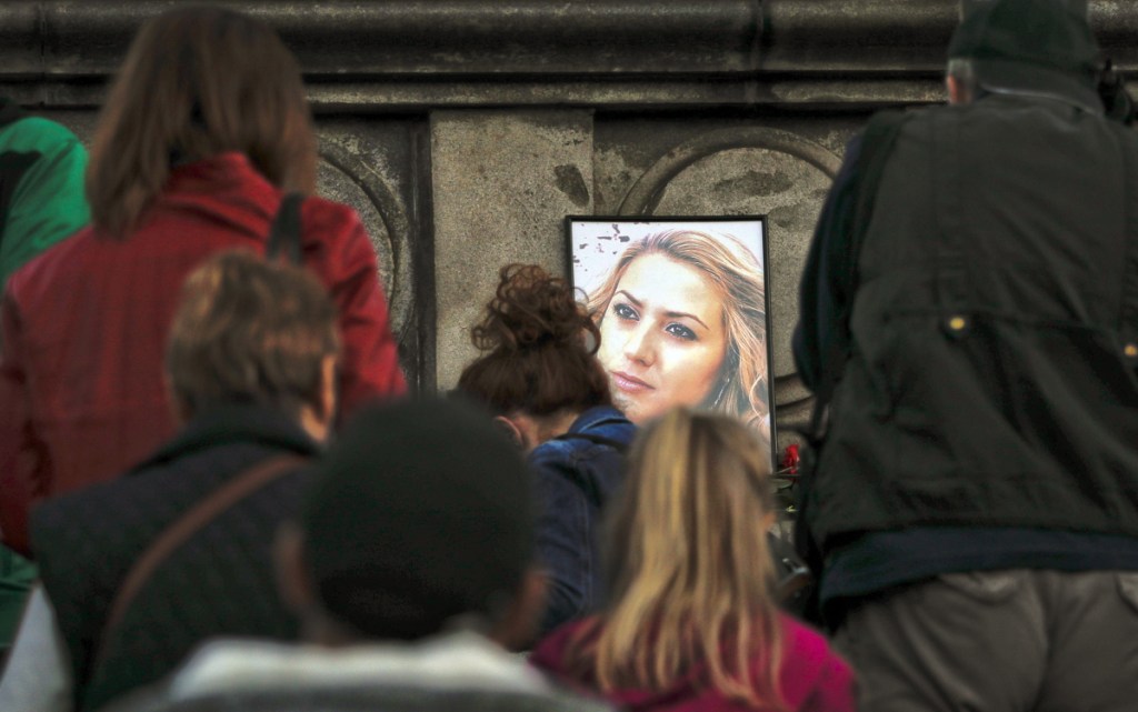 A portrait of slain television reporter Viktoria Marinova, above, is placed on the Liberty Monument in Ruse, Bulgaria, as people attend a vigil on Monday.
At left, a member of the Human Rights Association Istanbul branch, holds a poster with a photo of missing Saudi journalist Jamal Khashoggi, during a protest on Tuesday.