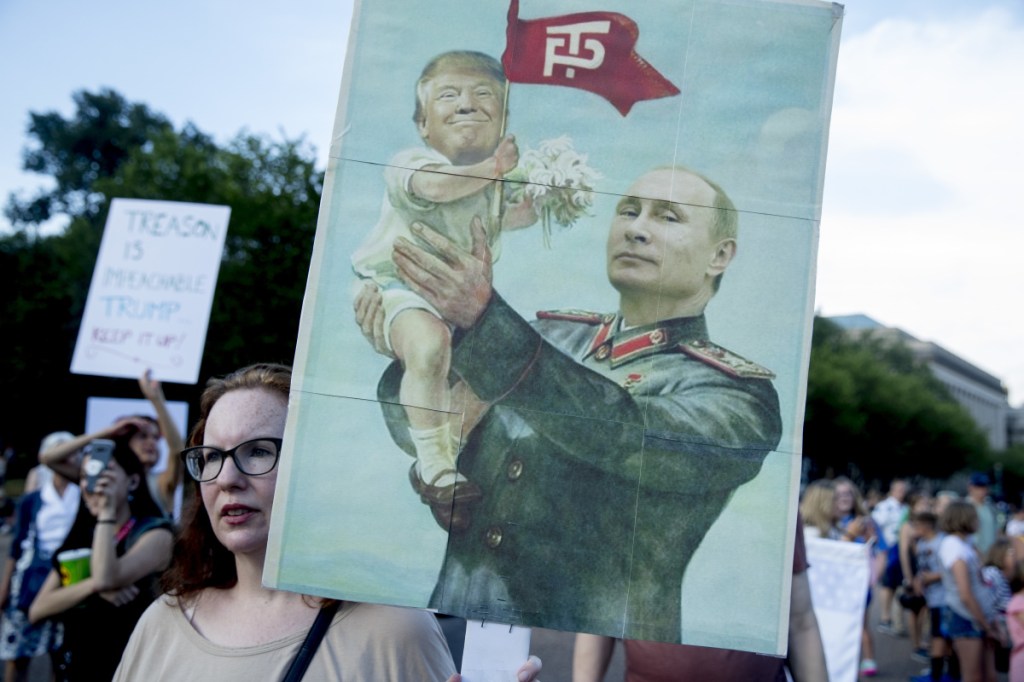 A woman holds a sign depicting Russian President Vladimir Putin and President Trump outside the White House in July.