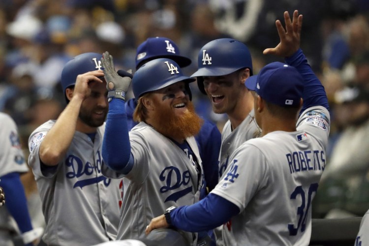 Dodgers sluggers Justin Turner, center, celebrates with Manager Dave Roberts, right, and teammates after hitting a go-ahead, two-run home run during the eighth inning of Game 2 of the NLCS against Milwaukee on Saturday. (AP Photo/Jeff Roberson)