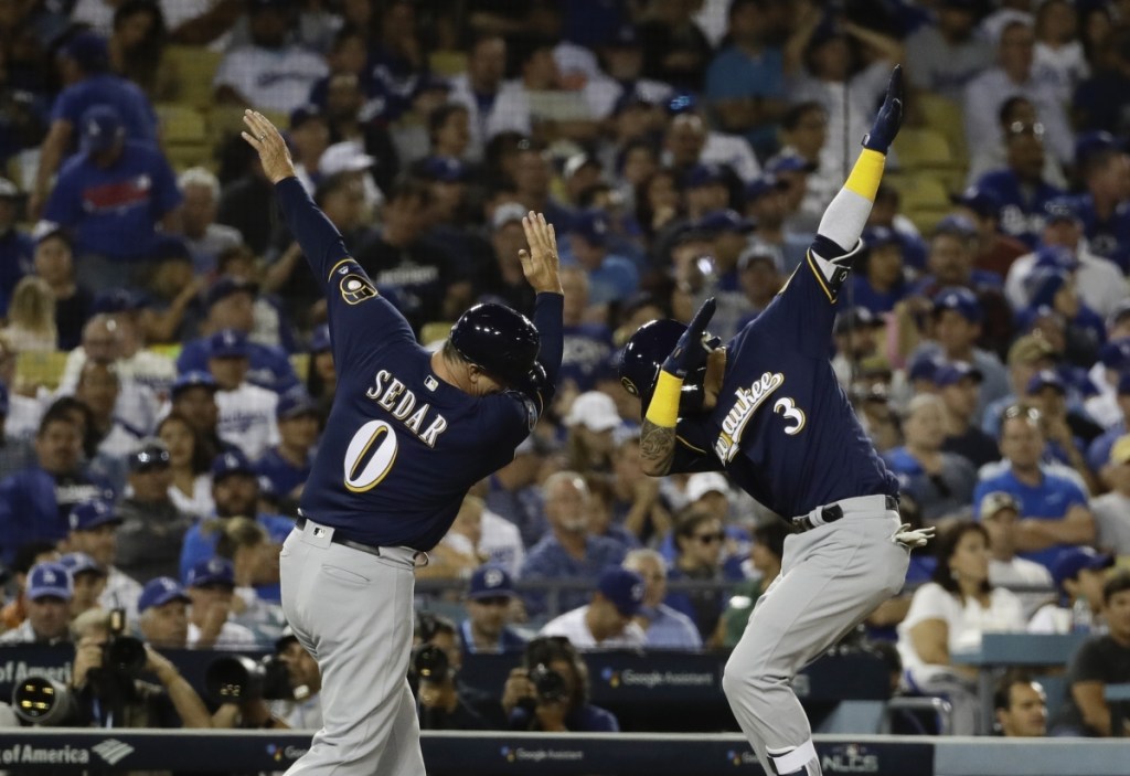 Milwaukee's Orlando Arcia celebrates his two-run home run with third-base coach Ed Sedar during the seventh inning of Game 3 of the NLCS Monday night in Los Angeles. The Brewers won, 4-0.