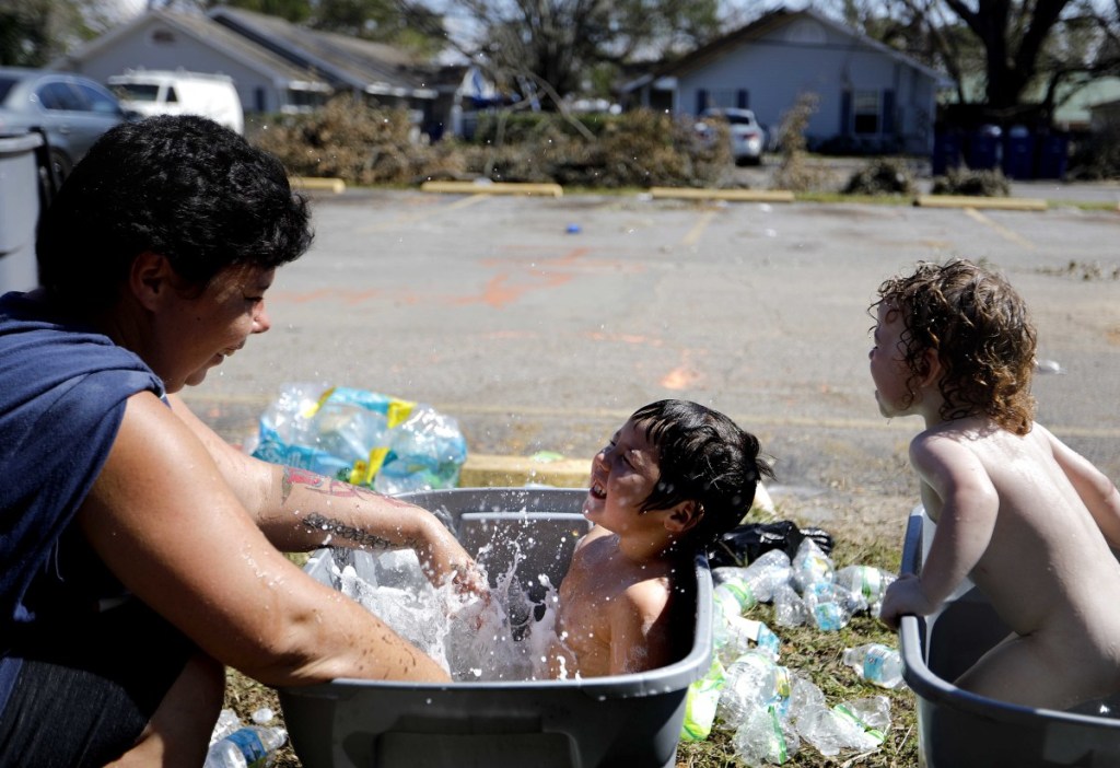 Tasha Hughes splashes her daughter Madison, 4, center, and a friend's son, Gaige Williams, 2, as they cool off in a storage container outside the damaged motel where they are living in the aftermath of Hurricane Michael in Panama City, Florida, on Tuesday. Many residents rode out the storm and have no place to go even though many of the rooms are uninhabitable.