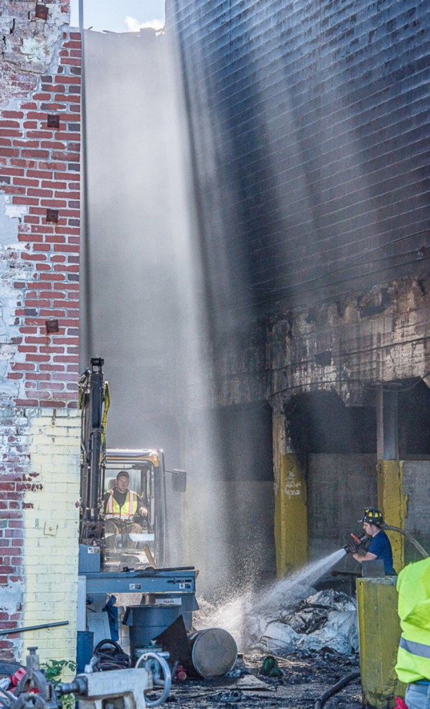 Mechanic Falls firefighters and public works personnel work on uncovering and soaking hot spots Tuesday, two days after a fire turned the former Marcal Paper Mill into mostly rubble.