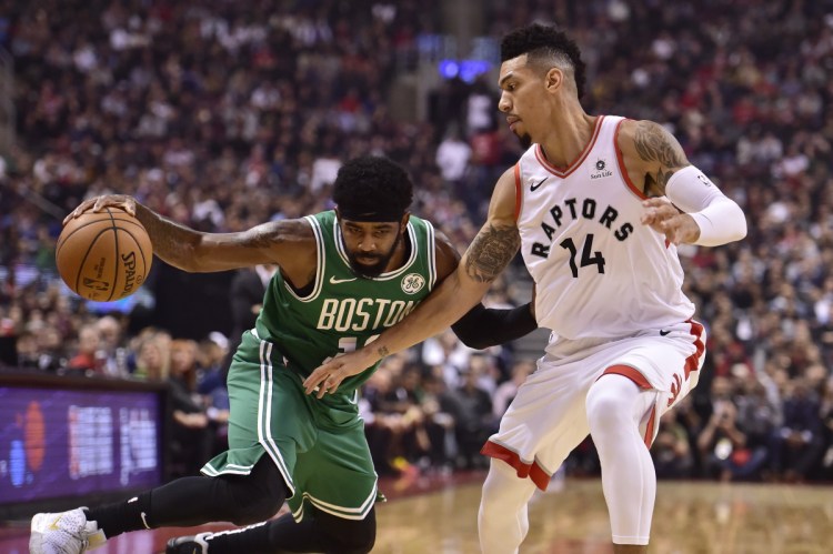 Celtics guard Kyrie Irving controls the ball as Toronto guard Danny Green defends during the first half Friday night in Toronto.