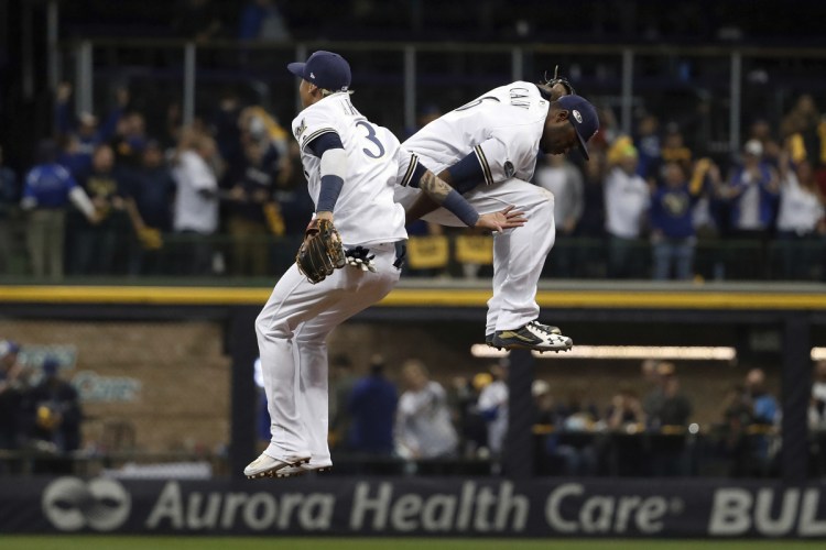 Milwaukee's Orlando Arcia (3) and Lorenzo Cain celebrate after Game 6 of the National League Championship Series against the Los Angeles Dodgers on Friday night in Milwaukee. The Brewers won 7-2.