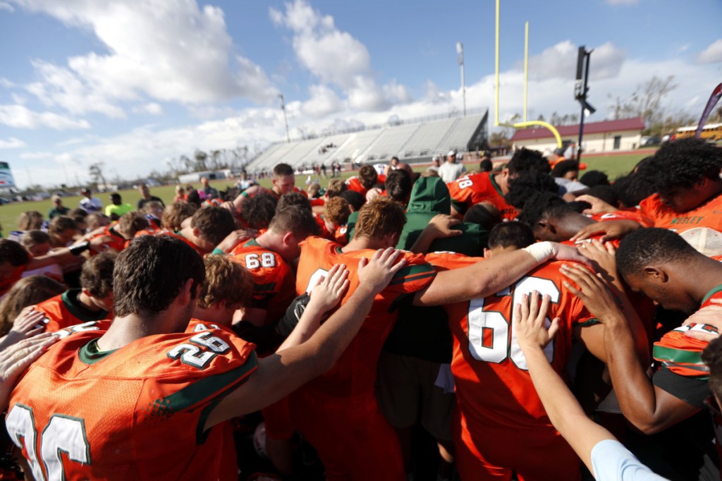 Coaches and players from Mosley High pray together after their loss Saturday to Pensacola High, in the aftermath of Hurricane Michael in Panama City, Fla.