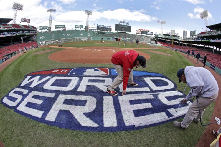 Grounds crew members paint the World Series logo behind home plate at Fenway Park on Sunday as they prepare for Game 1 of the World Series between the Boston Red Sox and the Los Angeles Dodgers on Tuesday.