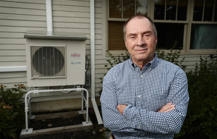 Mark Peterson outside his home in Saco with his exterior heat pump unit in the background. Peterson had three heat pump units and a heat-pump water heater installed two years ago and has not saved money or had better heating.