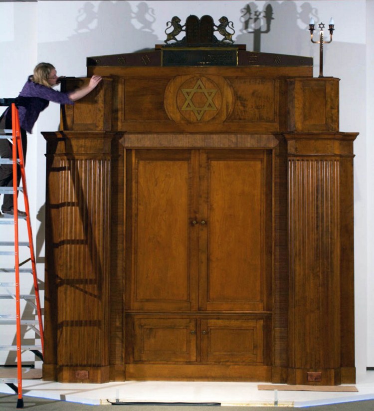 Maine State Museum objects conservator Teresa Myers makes final adjustments to the trim of the 1930s Torah ark once in the former Beth Abraham Synagogue in Auburn. The ark was meticulously disassembled and moved to the Maine State Museum for "Maine + Jewish: Two Centuries."