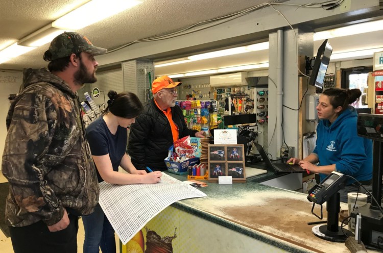 In West Gardiner, Four Corners General Store employees Dawn Hunt, right, and Jordan Shaw register Charles and Trevor Berry's deer.