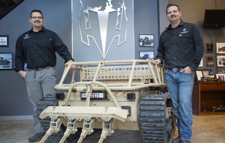 Brothers Michael, left, and Geoffrey Howe pose with their robot vehicle at their business in Waterboro. The company is growing, thanks to a major influx of capital from a defense industry giant.