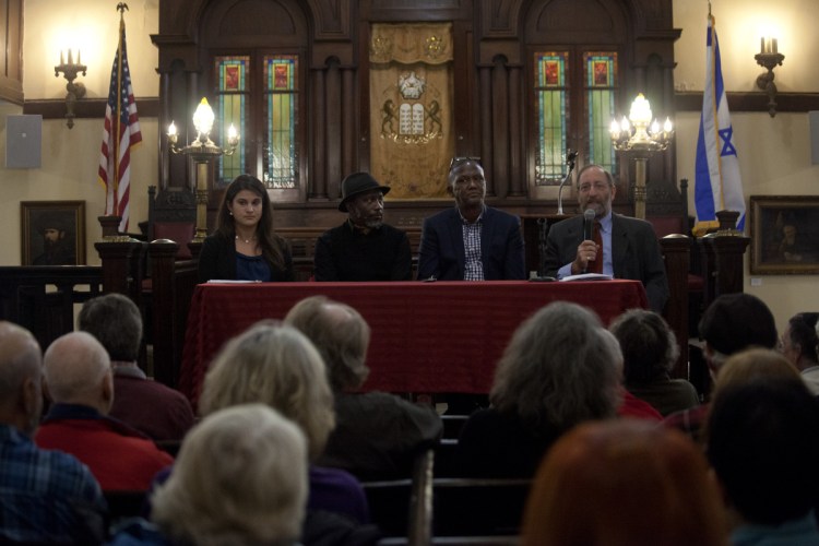 Rabbi David Fox Sandmel, right, reads the names of the victims of the shooting at the Tree of Life synagogue in Pittsburgh before hosting a panel with Amy Feinman, left, Pious Ali, Damas Rugaba at the Maine Jewish Museum in Portland on Sunday. (Staff Photo by Ariana van den Akker/Staff Photographer)