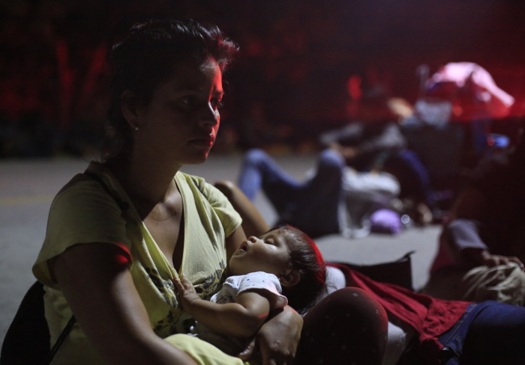 A woman holding her sleeping baby waits in hopes of hitching a ride, as a thousands-strong caravan of Central Americans continues its slow march toward the U.S. border, in Tapanatepec, Oaxaca state, Mexico, before dawn on Monday. Thousands of migrants traveling together for safety resumed their journey after taking a rest day Sunday, while hundreds more migrants were pushing for entry to Mexico.