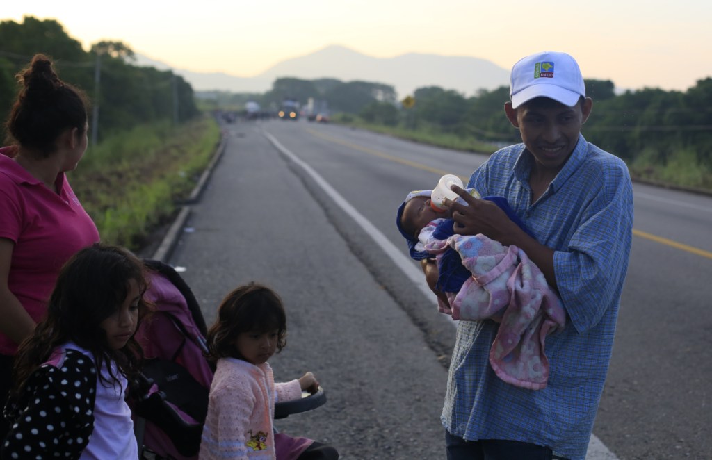 Guatemalan migrant Ernesto Cayax, 27, feeds his 25-day-old baby daughter, Reychel, as he takes a break from walking with his wife, Jahana Estrada, 23, and their three children, on the roadside outside Tapanatepec, Mexico, before dawn on Monday. The family joined up seven days ago with a thousands-strong caravan of Central Americans trying to reach the U.S. border, roughly 1000 miles away.