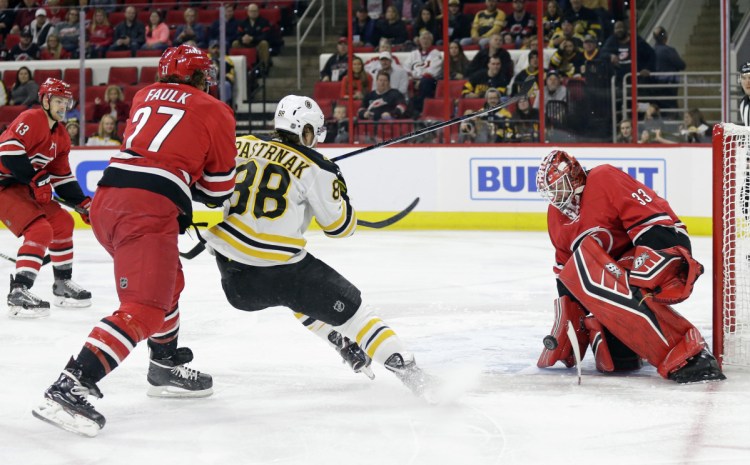 Carolina's goalie Scott Darling, a former UMaine goalie, blocks the net while Justin Faulk defends against Boston's David Pastrnak in the first period Tuesday night at Raleigh, N.C.