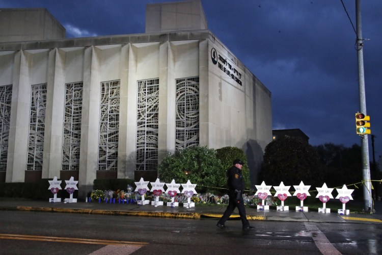 A Pittsburgh Police officer walks past the Tree of Life Synagogue and a memorial of flowers and stars on Oct. 28.
