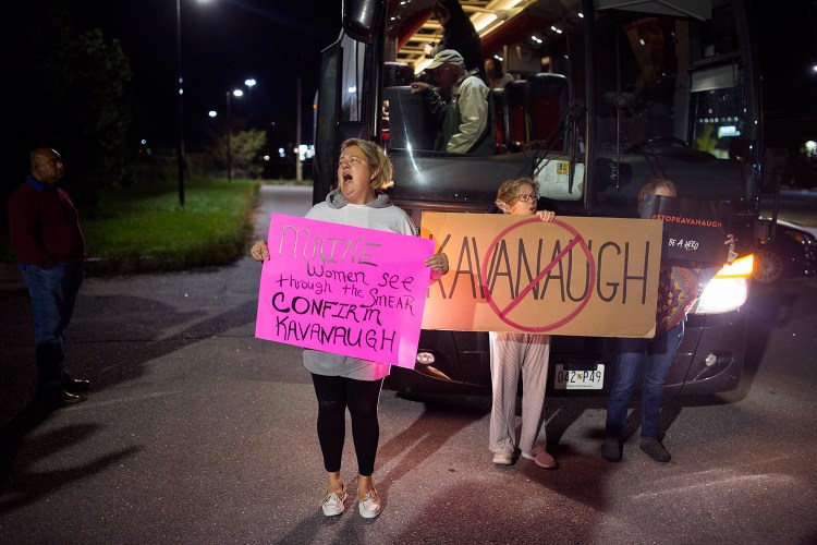 Susan Melcher of Pownal protests in front of the charter bus bound for Washington, D.C., from Portland on Wednesday night. The Mainers who left Portland, including Susan Feiner, holding an anti-Kavanaugh sign at center, hope to meet with Sen. Susan Collins to voice their concerns about Supreme Court nominee Brett Kavanaugh. Melcher, who supports Kavanaugh, said she decided to voice her opinion to stand up for Kavanaugh and his family.