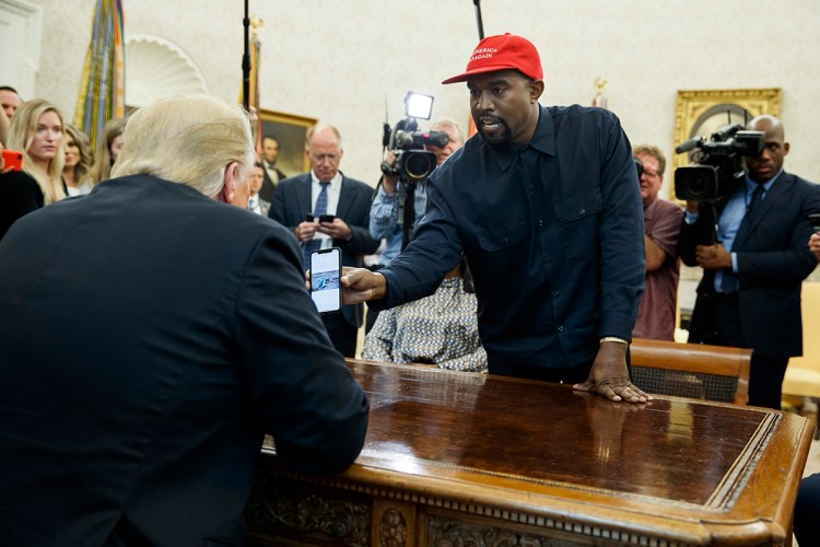 Rapper Kanye West shows President Trump a photograph of a hydrogen plane during a meeting in the Oval Office on Thursday.