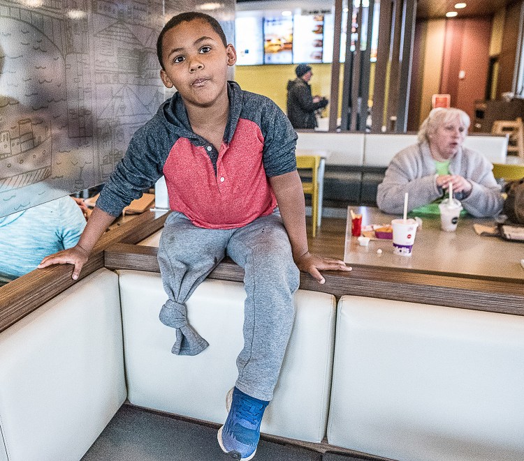 Adam Mattson, 5, was struck by a bucket loader last year and lost both of his legs. Doctors were able to reattach his left leg. His mother, Kim Mattson, sits behind him, at right, in the Farmington McDonald’s restaurant Wednesday.
