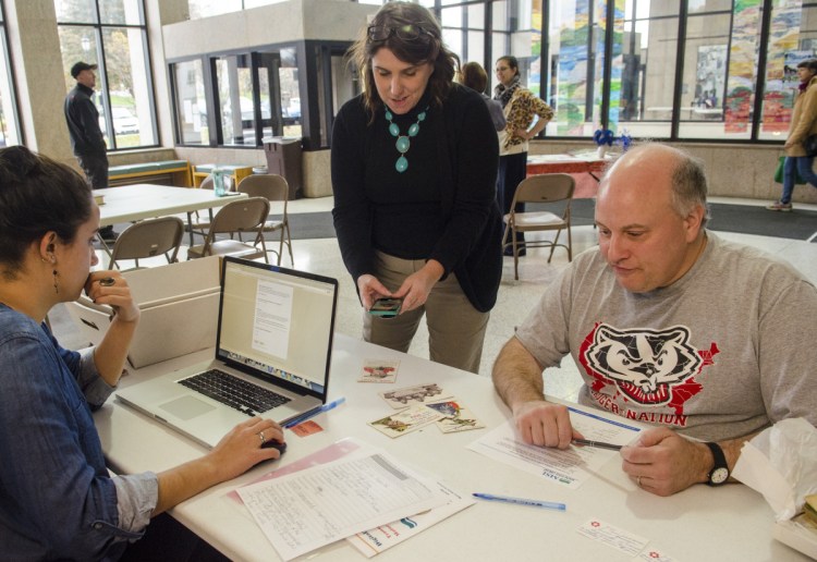 Adriana Ortiz-Burnham, left, and Christine Pittsley talk to Jim Melcher about the World War I postcard he brought in Saturday at the Cultural Building in Augusta. Pittsley works for the Connecticut State Library and was helping the run a digitization event with Maine state workers.