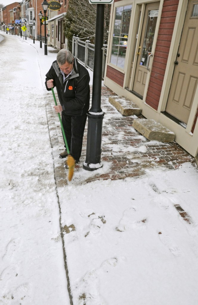 Jack Turner sweeps snow from from the sidewalk in front of his jewelry shop March 7, 2017, in downtown Hallowell. The City Council is considering a proposed ordinance that would require downtown-area commercial property owners to clear snow from the sidewalks in front of their buildings.