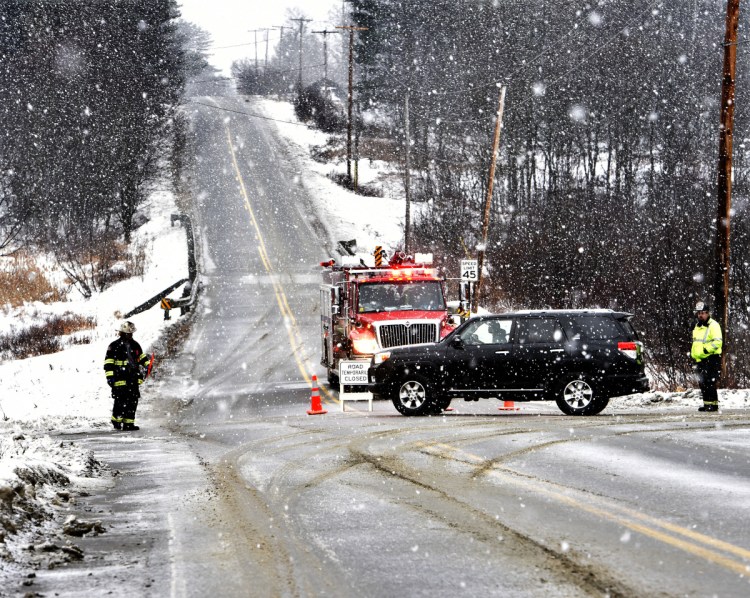 Firefighters from Madison detour traffic Sunday at the intersection of Route 43 and Molunkus Road in Cornville as police, working in falling snow, investigate a fatal accident on Route 43.