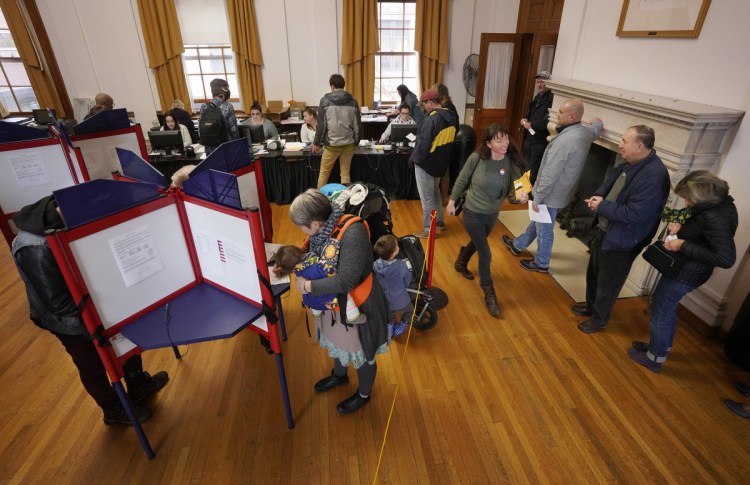 Early voters crowd the booths at Portland City Hall at lunch hour Thursday, the last day Maine residents could pick up absentee ballots. Absentee ballots must be turned in to municipal clerks by 8 p.m. on Election Day, next Tuesday.