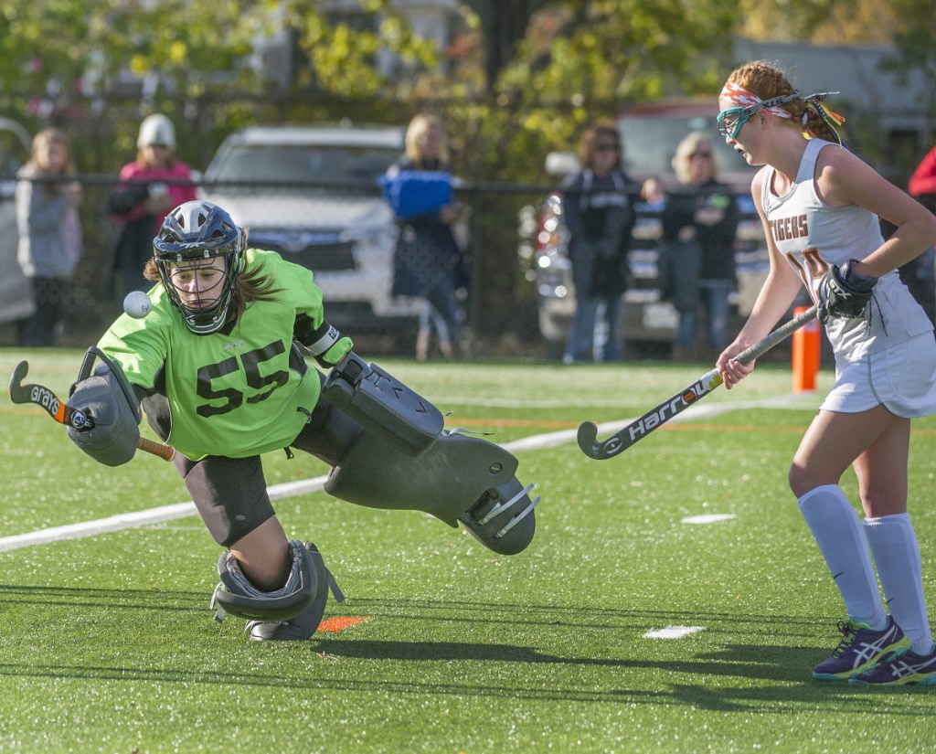 Biddeford goalie Taylor Wildes makes a stick save on a Falmouth shot. Defender Harmonie Coolbroth looks to help on the play. (Staff photo by John Ewing/Staff Photographer)