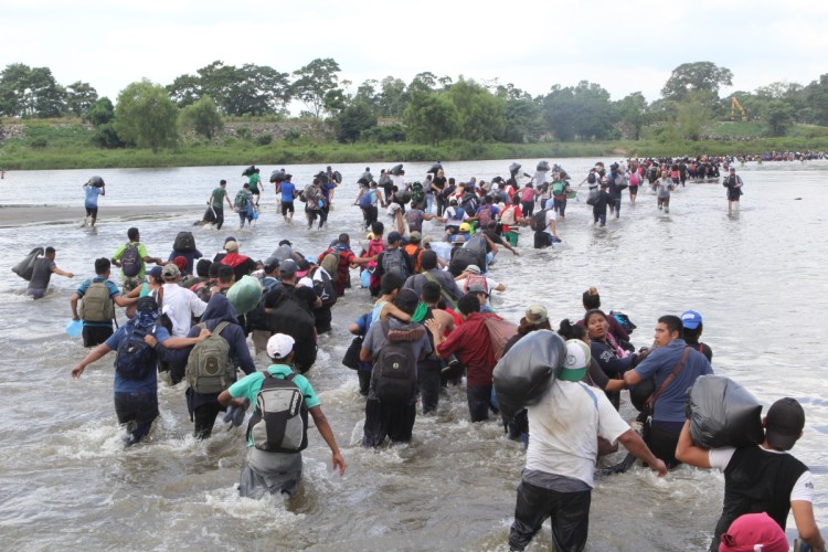 Salvadoran migrants wade across the Suchiate River, between Guatemala and Mexico, on Friday after Mexican officials told them they would have to show passports and visas and enter in groups for processing.